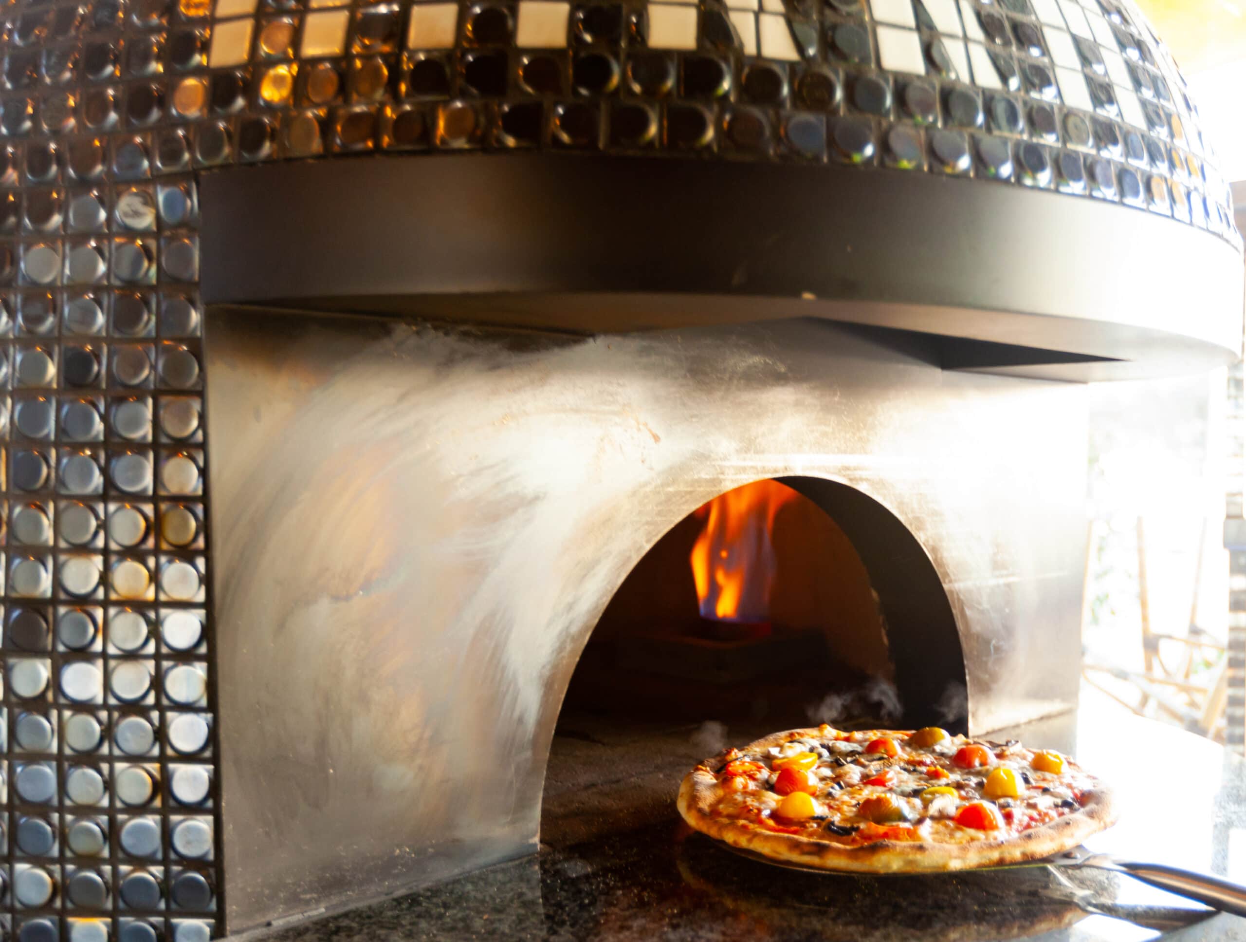 Round pizza cooking in the Pizzeria Del Sol stone oven
